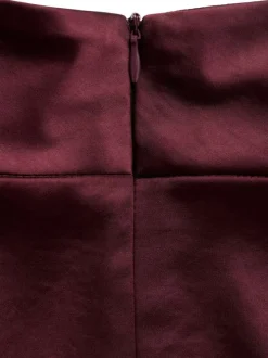 Blouse bordeaux en tissu satiné sans manches pourvue d'un col montant