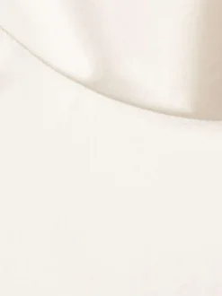 Blouse écrue en tissu satiné sans manches pourvue d'un col montant