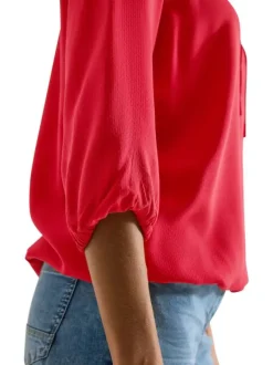 Blouse rouge unie pourvue d'une coupe large et d'un col tunisien