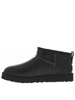 Boots en cuir noires à talon plat avec des surpiqûres noires et blanches