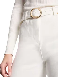 Jean blanc uni avec une coupe bootcut et une ceinture à boucle dorée