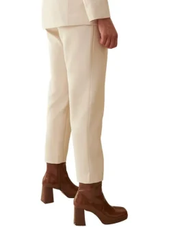 Pantalon beige uni avec une coupe slim et logo de la marque en bijou argenté