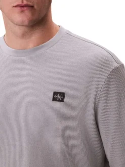 Pull gris clair uni texturé avec un petit patch brodé et à col rond