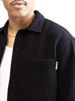 Surchemise noire en maille effet gaufrée pourvue d'un col à revers