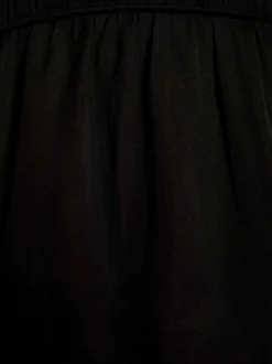 Top à fines bretelles noir uni avec une coupe péplum et un col v