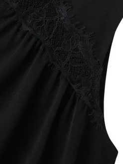 Top noir uni avec une coupe ajustée et des empiècements en dentelle