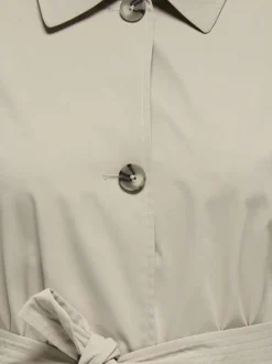 Trench coat beige pourvu d'un col à revers et d'une ceinture à nouer