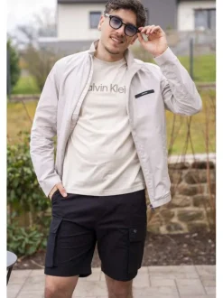 Veste blanche légère avec un aspect satiné un col montant et des poches